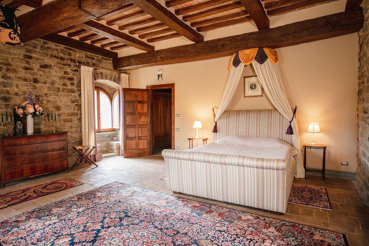 Camera luminosa del castello con pareti in pietra, travi in legno e letto a baldacchino